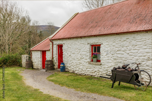Traditional red painted irish cottage with a wheelbarrow