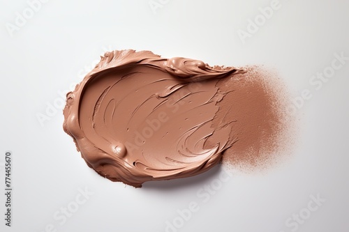 A swatch of cream foundation is artfully spread on a neutral-toned background, highlighting the products creamy texture and specific skin-tone shade.