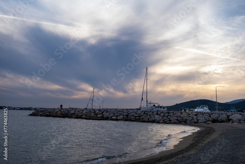 Sunset on the sea with rocks and houses in the background. Yachts and boats on the shore of the sea at sunset