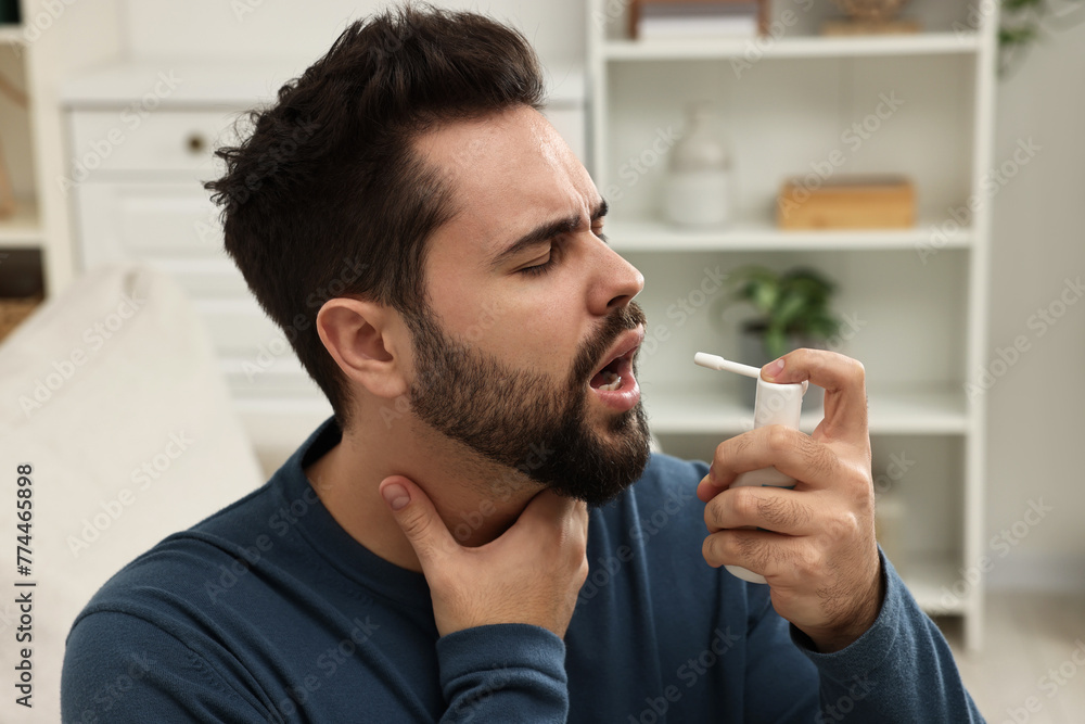 Young man using throat spray at home Young man using throat spray at home