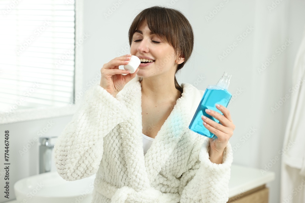 Young woman using mouthwash in bathroom. Oral hygiene Young woman using mouthwash in bathroom. Oral hygiene