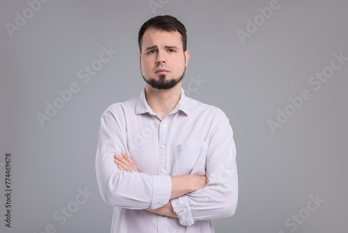 Portrait of sad man with crossed arms on grey background