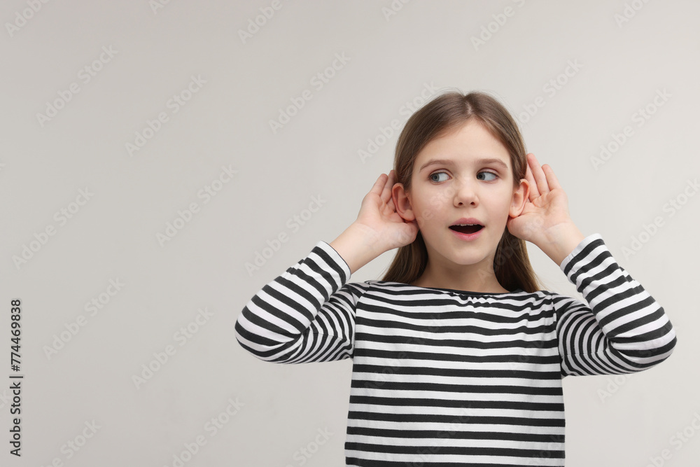 Little girl with hearing problem on grey background, space for text Little girl with hearing problem on grey background, space for text