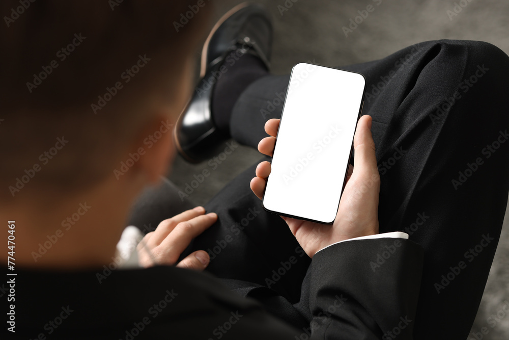 Naklejka premium Man using smartphone with blank screen indoors, closeup. Mockup for design