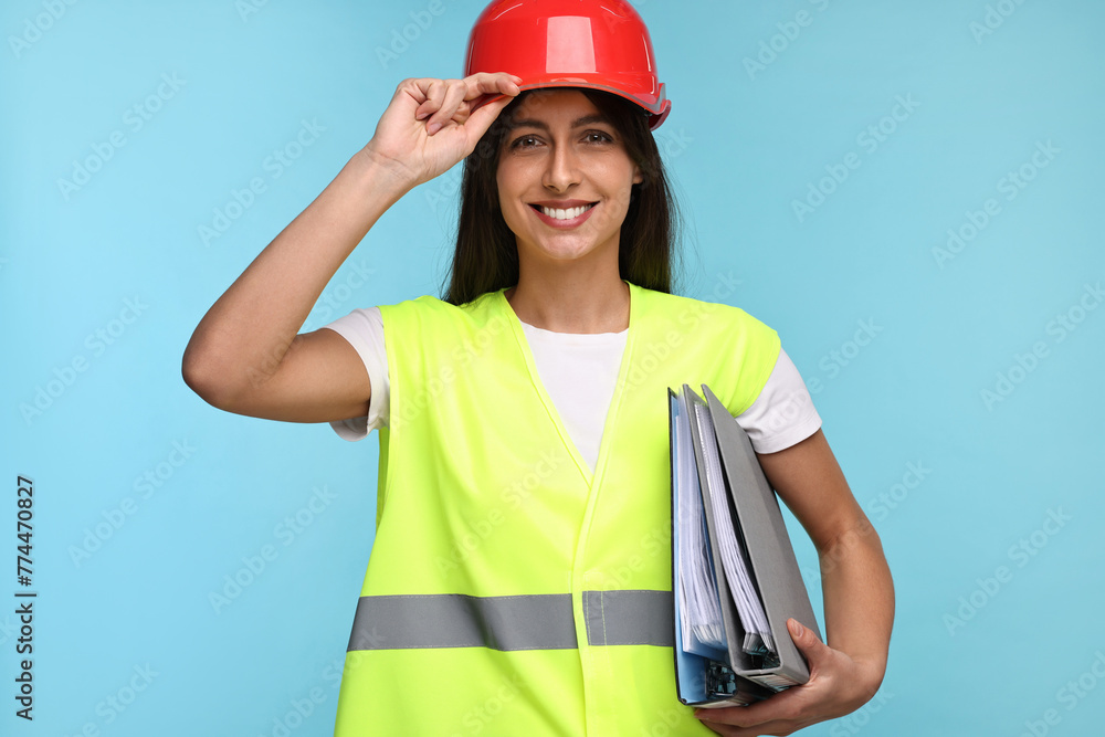 Architect in hard hat with folders on light blue background Architect in hard hat with folders on light blue background