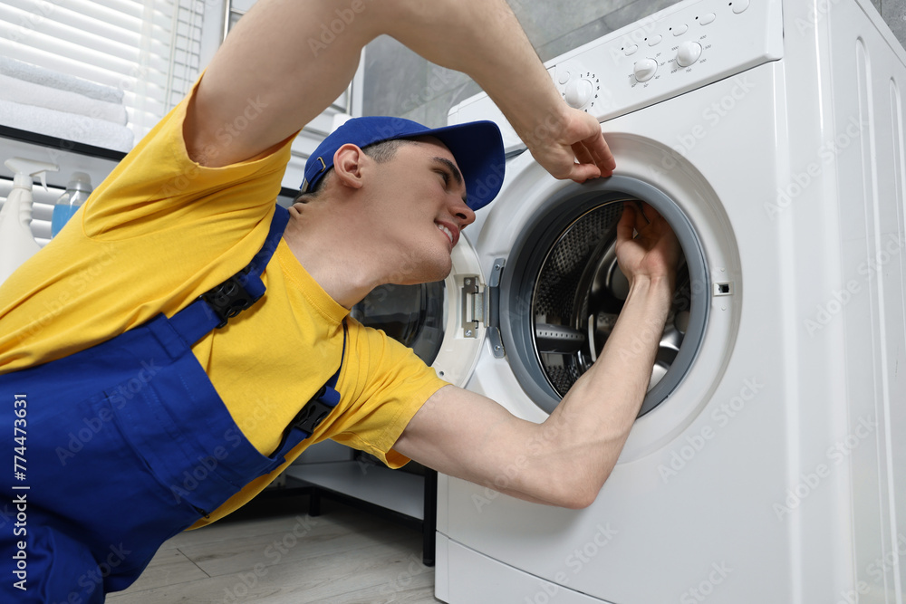Smiling plumber checking door gasket of washing machine Smiling plumber checking door gasket of washing machine