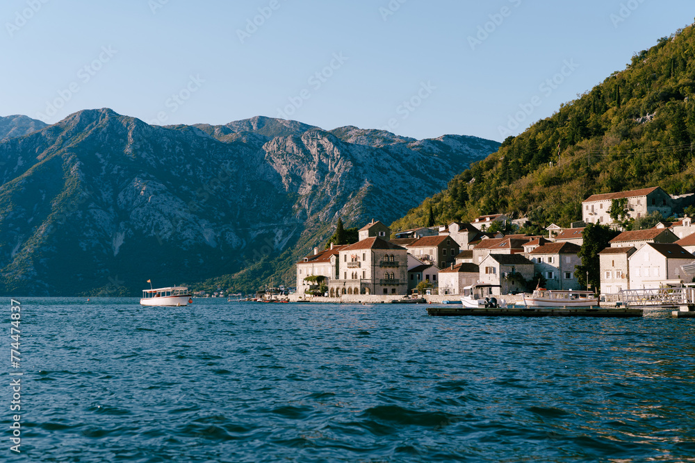 Boats float on the sea off the coast of Perast at the foot of the green mountains. Montenegro