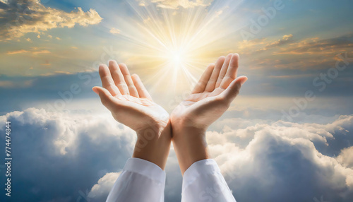 praying human hands towards  divine light and the clouds in the sky