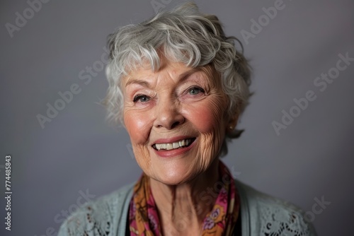 Portrait of a happy senior woman smiling at the camera on a gray background