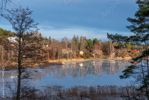 Lake in spring. Beautiful spring landscape with melting ice on blue water of lake and larches