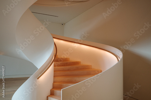 Interior staircase featuring a smooth curve, with warm light emanating from the built-in illumination along the handrail. 