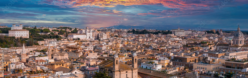 An aerial view of Rome at dusk reveals terracotta rooftops, church domes, and spires against a sunset. White buildings and mountains highlight the city's ancient modern mix.