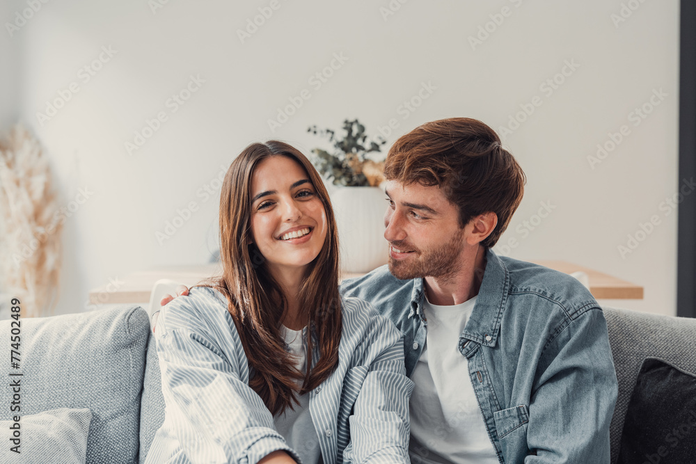 Portrait of young 20s just married couple in love posing photo shooting seated on couch in modern studio apartments, concept of capture happy moment, harmonic relationships, care and sincere feelings. Portrait of young 20s just married couple in love posing photo shooting seated on couch in modern studio apartments, concept of capture happy moment, harmonic relationships, care and sincere feelings.