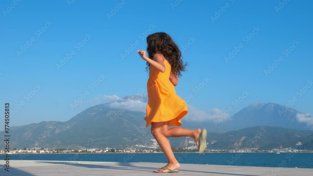 A happy child is spinning. Charming little girl is spinning on the seashore. A happy child is spinning. Charming little girl is spinning on the seashore.