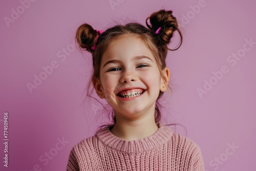 Portrait of a smiling little girl in a pink sweater on a pink background