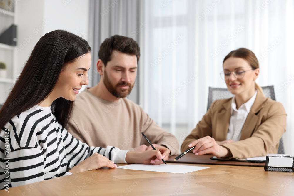 Couple signing document while having meeting with lawyer in office, selective focus Couple signing document while having meeting with lawyer in office, selective focus