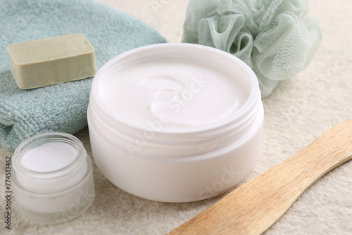 Body care cream in open jars on light textured table, closeup