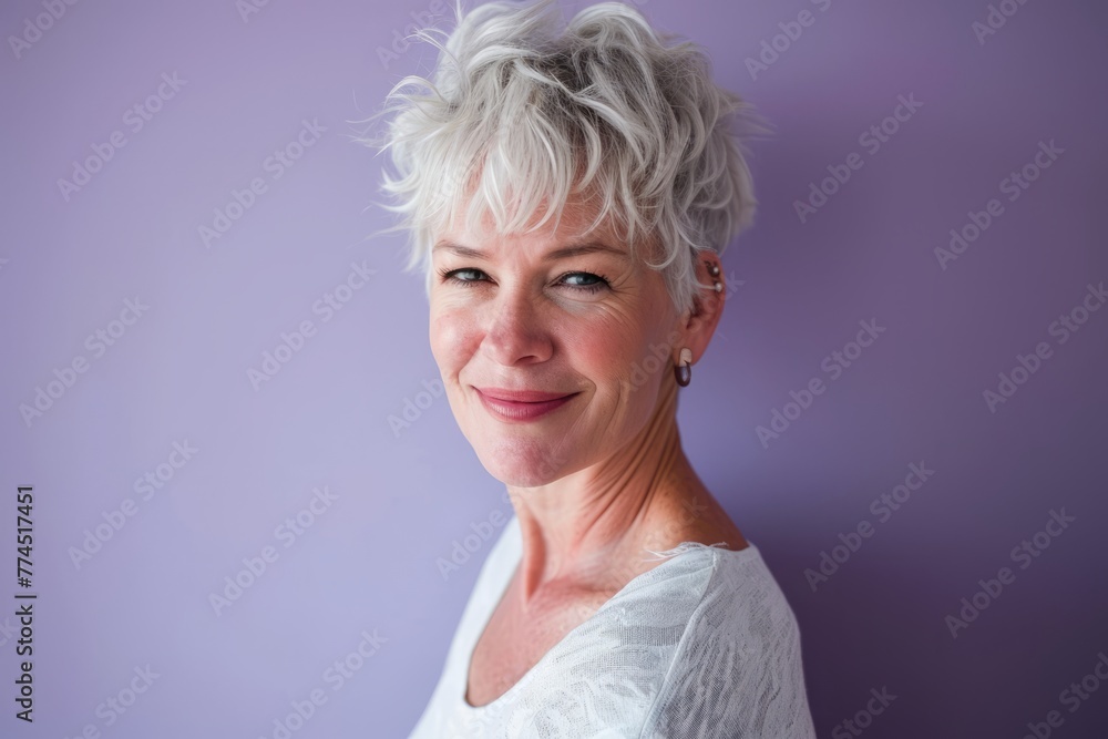 Portrait of a beautiful mature woman with short white hair against purple background