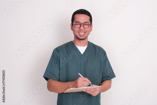 Asian nurse smiling at the camera while writing patient medical report photo