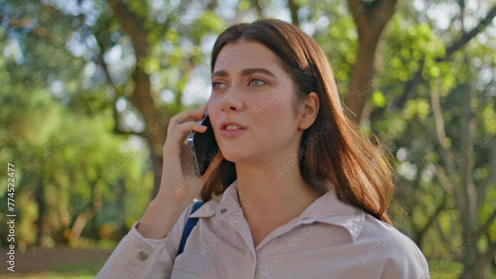 Annoyed woman talking cellphone looking frustrated walking green park closeup. Annoyed woman talking cellphone looking frustrated walking green park closeup.