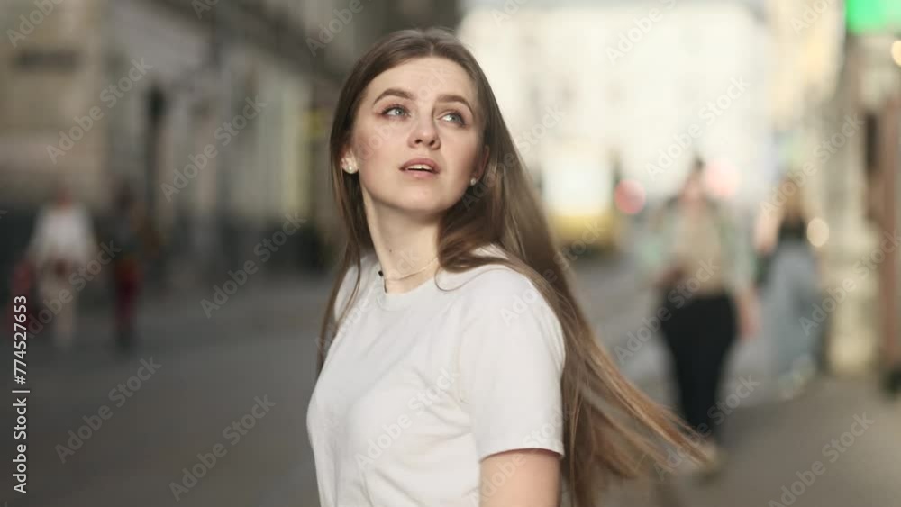 Charming young woman with long hair walking down the street turns around with flying hair outdoors Happy relaxed tourist walking on the city centre enjoying beautiful day alone Charming young woman with long hair walking down the street turns around with flying hair outdoors Happy relaxed tourist walking on the city centre enjoying beautiful day alone
