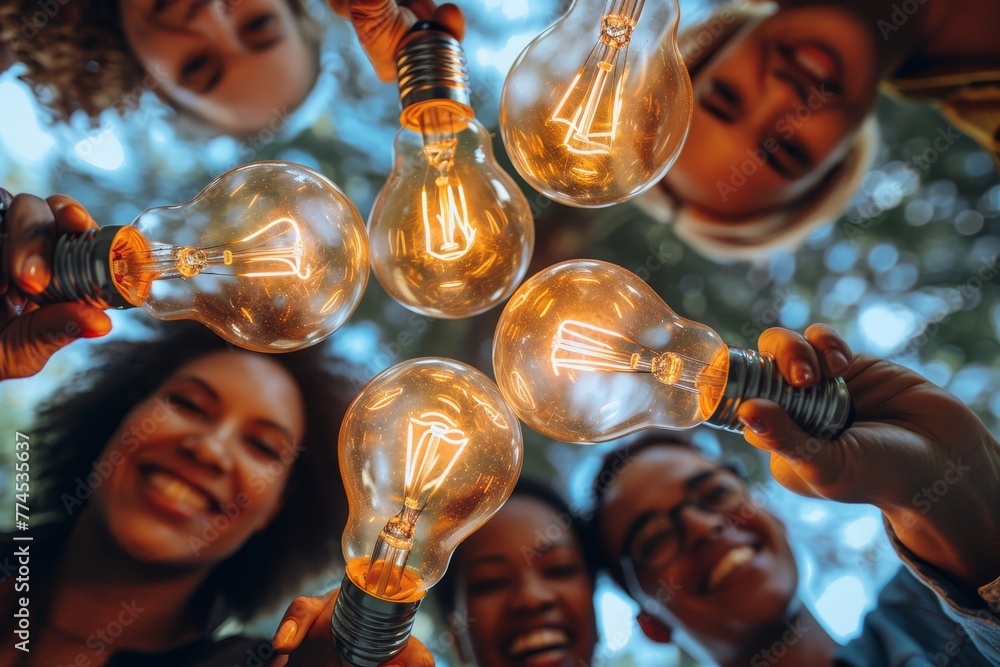 Bottom view of interracial colleagues stacking together light bulbs as ...