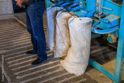 A man stands in front of machine with bags of white material on it