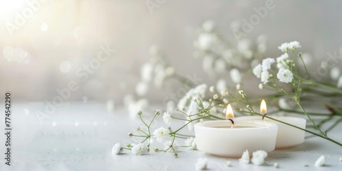 A white candle placed on a table next to a bouquet of white flowers