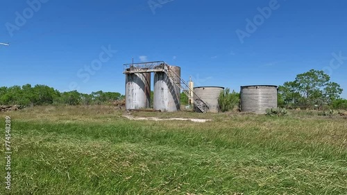 Old oilfield tanks in a field along the side of the road in Wilson County near the city of Floresville (ID: 774548289)