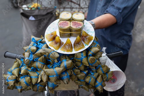 Vietnamese street food vendor selling banh chung chay and banh gio mat from his motorbike.