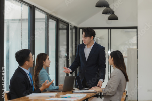 A group of employees happily work together in the office while discussing work that was completed on time as ordered by their boss, A group of entrepreneurs had fun working together.