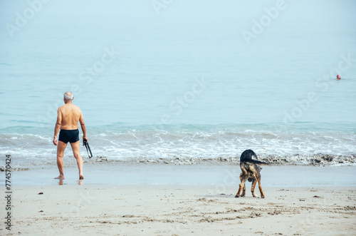 Senior man and dog enjoying beach walk