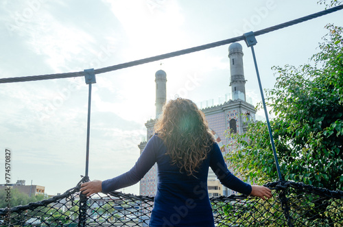 Woman gazing at mosque from balcony