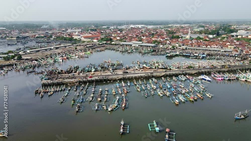 The view of Muncar port, packed with old-style boats parked there, shows the biggest traditional fish port in Java. aerial 4k drone footage- wide shot.  photo
