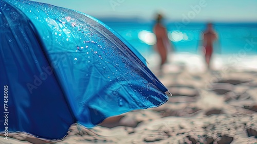 Summer Vibes: A blue beach umbrella stands out against the playful backdrop of seaside fun. © Alex