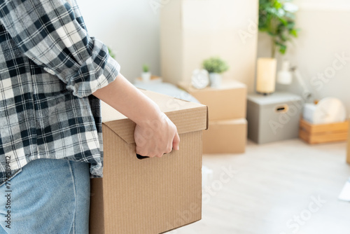 Moving house, relocation. Woman hold carton box contain equipment for new condominium, inside the room was a cardboard box containing personal belongings and furniture. move in the apartment