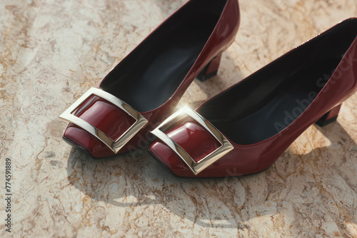 Elegant red high heel shoes with golden buckles on marble surface photo