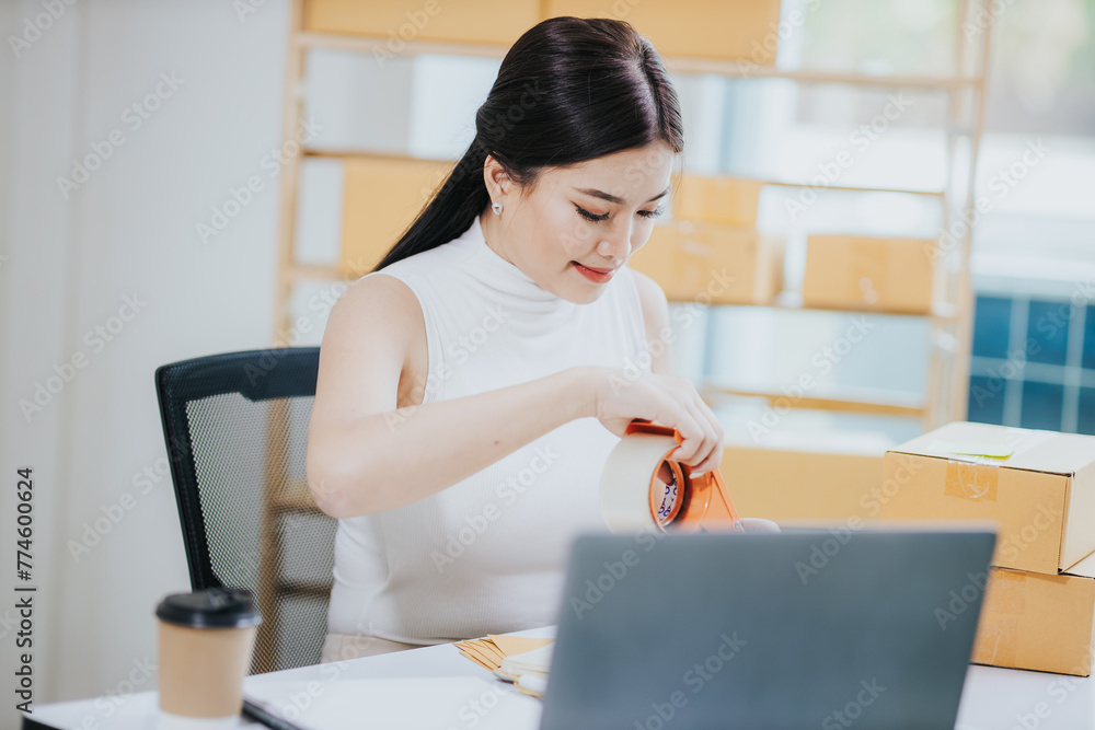Obraz premium Small business entrepreneurSME Freelance Asian woman working at home using laptop computer and boxes Cheerful successful Asian woman Online marketing and SME delivery ideas