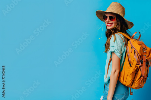 happy girl going on a trip, a girl in glasses and a hat with a backpack on a blue background, space for text, summer trip