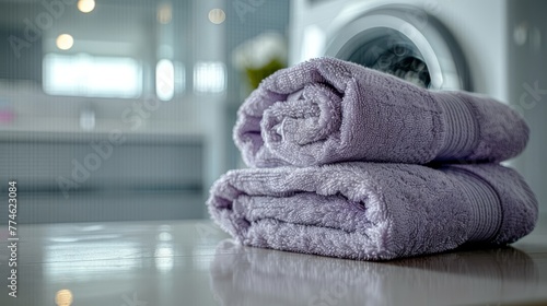  A pile of purple towels on a counter with a washer and dryer in a bathroom