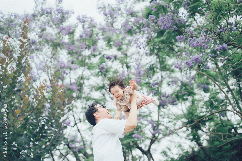 Naklejka premium ジャカランダの木と高い高いされる赤ちゃん