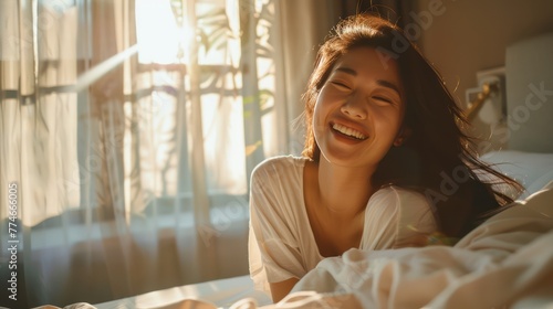 A Happy half Asian woman getting out of bed in the morning laughing. Happiness, waking up, relaxing, welcoming the new day.