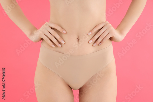 Slim girl in pink underwear, on a pink background. © Atlas