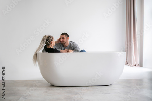 Man and Woman Engaging in Conversation While Sitting at Opposite Ends of a Modern Bathtub