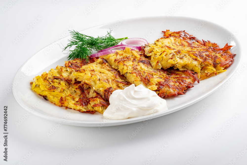 Fried Potato pancakes with sour cream in a white plate on a white background. Grated potatoes fried in oil Fried Potato pancakes with sour cream in a white plate on a white background. Grated potatoes fried in oil