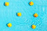 Top view yellow rubber ducklings floating on blue water of swimming pool.