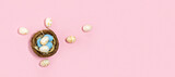 Top view Easter eggs in nest on pink background. Wide banner.