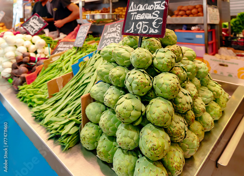 A stall with fresh baby green artichokes, green beans and other vegetables at a farmers market in Malaga, Spain.