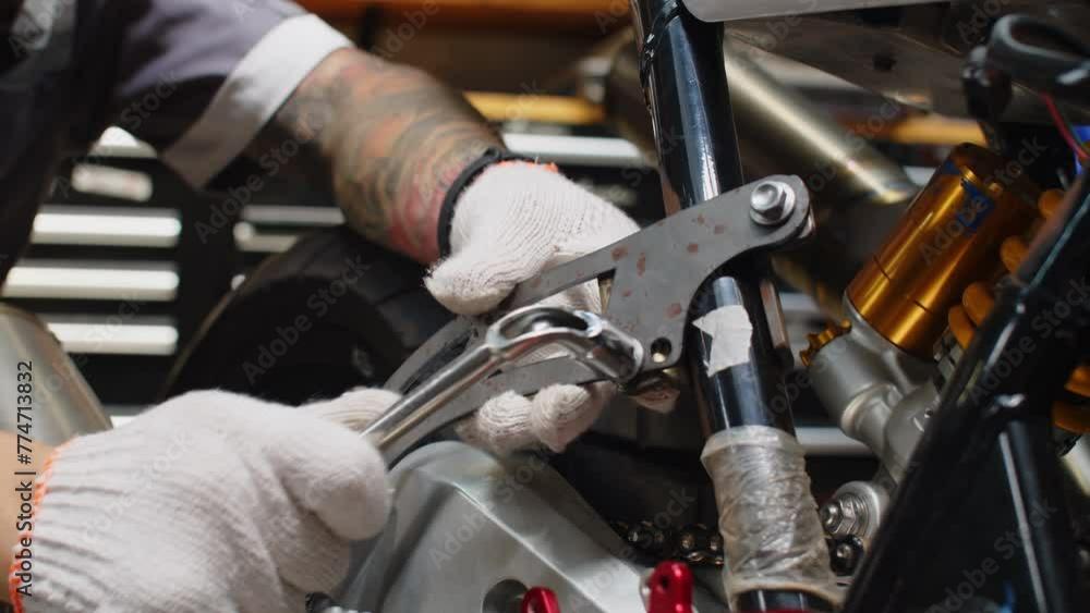 Close up of hands of unrecognizable mechanic wrenching detail of broken clients motorcycle Close up of hands of unrecognizable mechanic wrenching detail of broken clients motorcycle