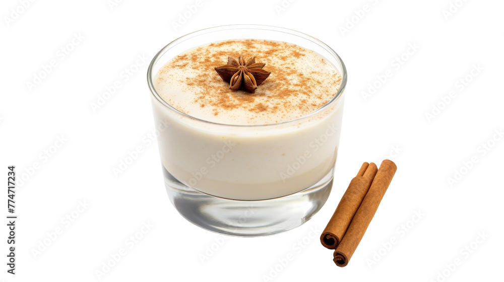 A glass of milk sits beside cinnamon sticks on a white background A glass of milk sits beside cinnamon sticks on a white background
